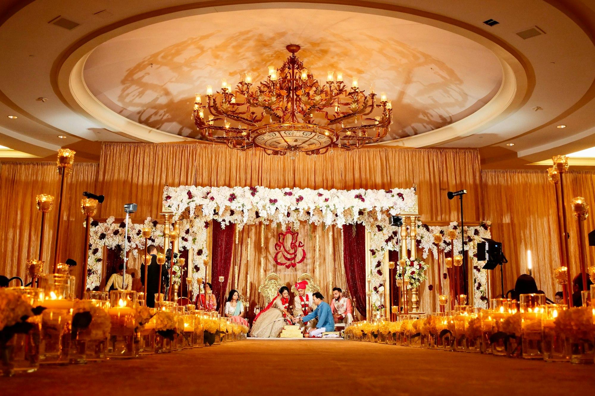 A couple seated at a candlelit mandap during their wedding ceremony