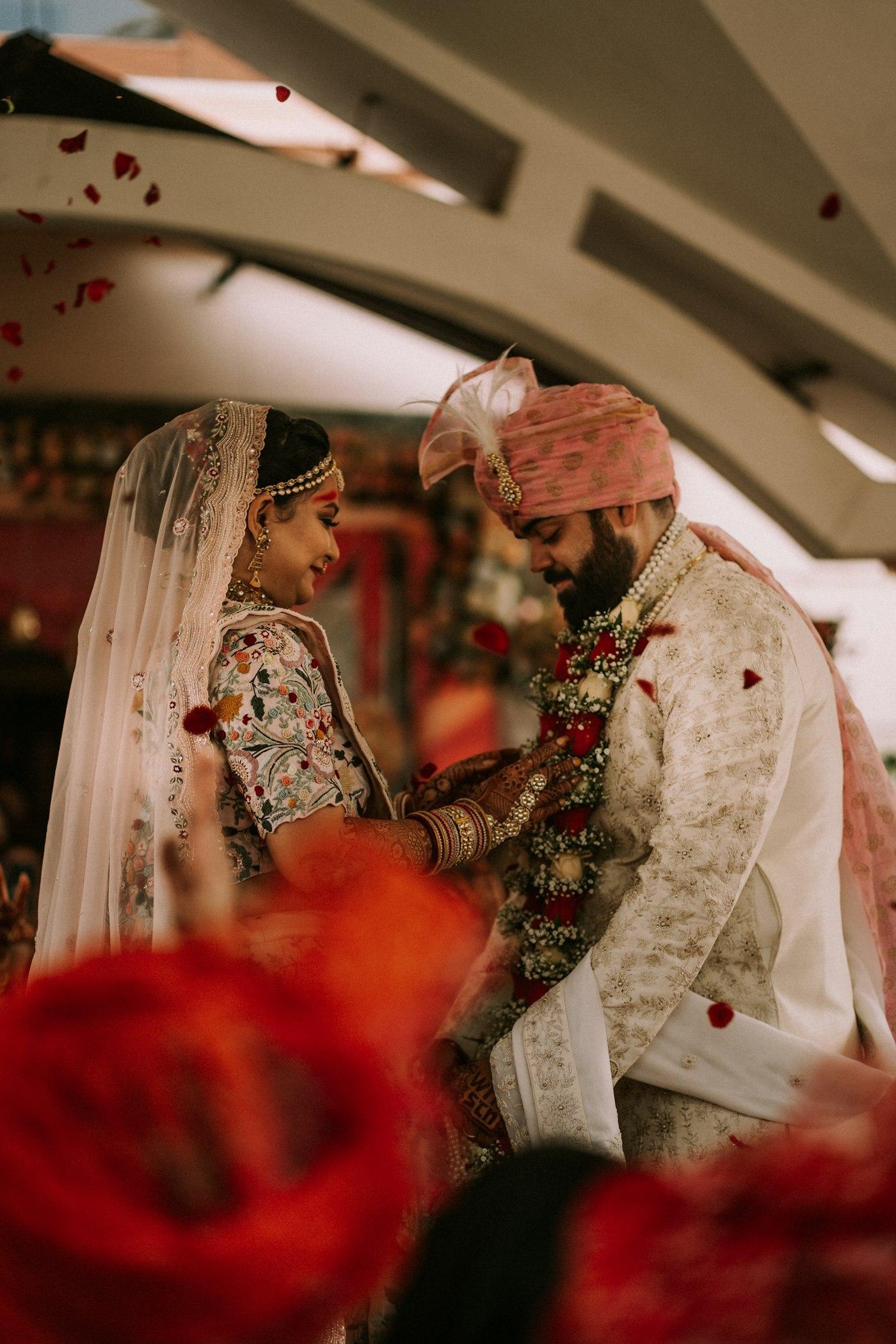 A couple facing each other beneath a shower of rose petals
